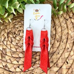 the red bow earrings are on display next to some plants