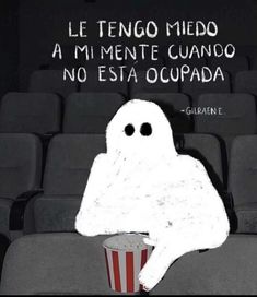 a ghost sitting on top of a chair next to a cup with popcorn in it