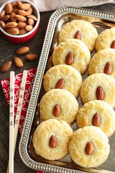 almond cookies are arranged on a metal tray next to some nuts and a red napkin