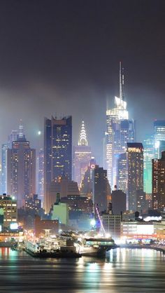 the city skyline is lit up at night with bright lights on it's skyscrapers