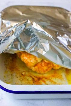 the chicken is wrapped in tin foil and ready to be cooked on the stove top