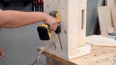 a man is working on a piece of wood with tools in his hand and two screwdrivers