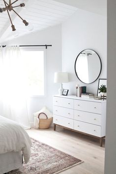 a bedroom with white furniture and a large mirror on the wall next to a bed