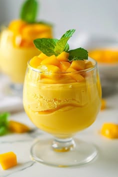 two glasses filled with yellow dessert and garnished with mint on the rims