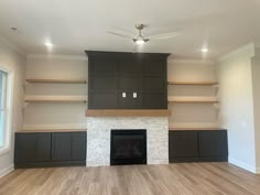 an empty living room with built - in shelves and a fireplace