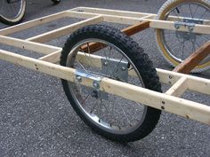 two bikes are parked next to each other on the pavement and one is made out of plywood