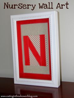 a red and white frame with the letter n in it on top of a wooden table