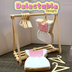 a cookie shaped like a baby's dress hanging on a clothes rack with clothes