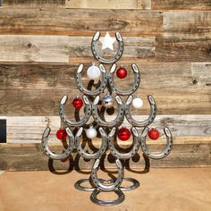 a christmas tree made out of horseshoes and balls on a wooden surface with wood planks in the background