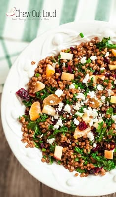 a white plate topped with lentils, cheese and oranges on top of a wooden table