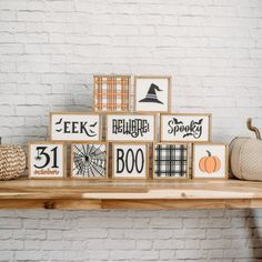 wooden blocks decorated with black and white pumpkins are sitting on a shelf in front of a brick wall