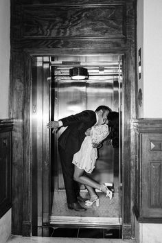 a man and woman kissing in an elevator while standing next to each other on their knees