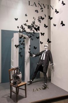 a man in a suit and tie standing next to a chair with butterflies on it