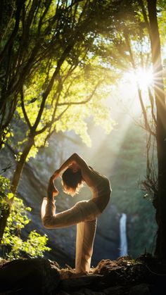 a woman doing yoga in the woods with sunlight streaming through her hair and trees behind her