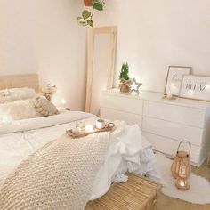 a bedroom with white walls and wooden flooring is lit up by candles on the nightstands