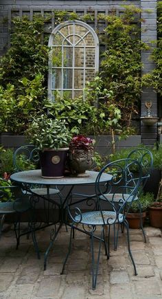 an outdoor table and chairs with potted plants