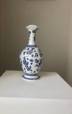 a blue and white vase sitting on top of a table next to a framed painting