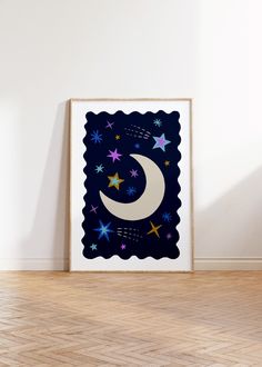 a poster with the moon and stars on it in front of a white wall, next to a wooden floor