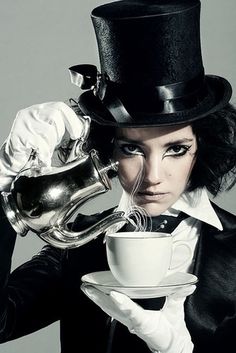 a woman wearing a top hat and holding a teacup with whisk in it