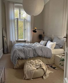 a bedroom with a large bed and lots of pillows on the floor in front of a window