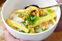 a person holding a white bowl filled with rice and vegetables