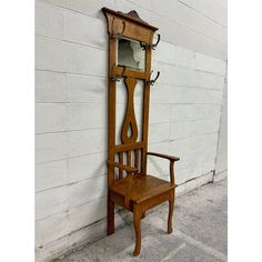 an old wooden chair sitting next to a wall with a mirror on it's back