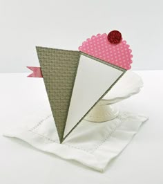 an origami paper piece with a pink heart on it sitting on top of a napkin