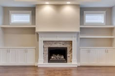 an empty living room with built - in shelves and a fireplace