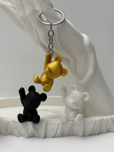 two small black and white teddy bears hanging from a metal keychain on a table