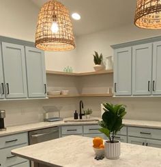 a kitchen with blue cabinets and white counter tops, two hanging lights above the island