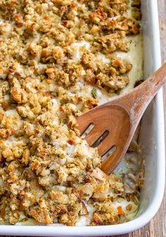 a casserole dish with meat and cheese in it, topped with a wooden spoon