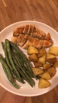 a white plate topped with chicken, potatoes and green beans