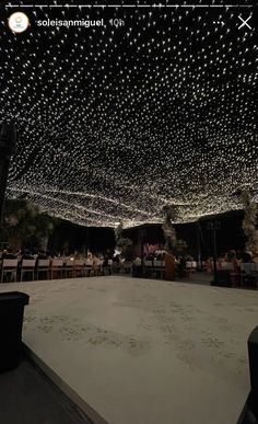 the ceiling is covered with hundreds of white lights and people are sitting at tables in front of them