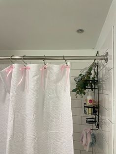 a shower curtain with pink bows hanging from it's side next to a white tiled wall