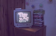 an old tv sitting on top of a wooden table next to a pile of dvds