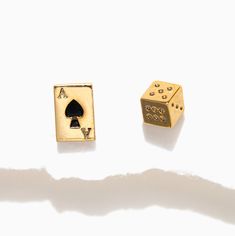 two gold dices and a playing card on a white surface with shadow from the back