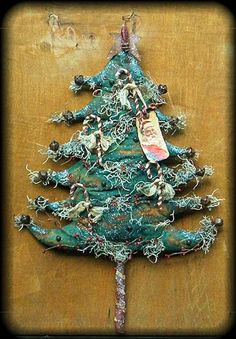 a christmas tree made out of wire and beads on a wooden surface with a tag hanging from the top