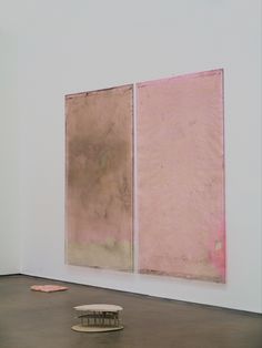 two paintings are hanging on the wall in an art gallery, one is pink and the other is brown