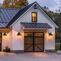 a white house with two garages and lights on the front door is lit up at night