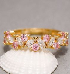 two gold rings with pink and white stones sitting on top of a sea urn