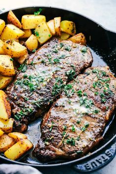 two steaks with potatoes and parsley on a black plate, ready to be eaten