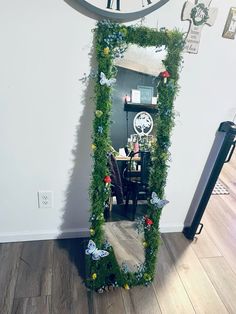 a mirror that is sitting on the floor in front of a wall with plants growing out of it