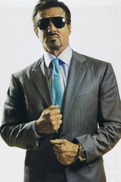 a man in a suit and sunglasses is holding his hand out to the side,