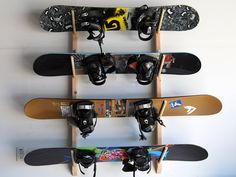 three snowboards mounted to the side of a wall with shoes hanging on it's sides