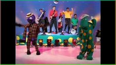 a group of people standing on top of a stage in front of a green frog