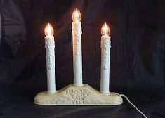 three white candles are lit on a stand