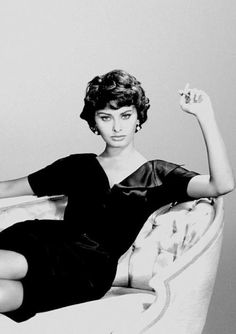 black and white photograph of a woman sitting on a chair with her arm in the air