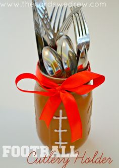 a mason jar with utensils in it and a red ribbon tied around the top