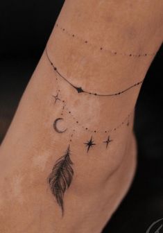 a foot with a tattoo on it that has stars and a feather hanging from the ankle