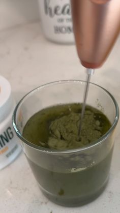 a cup filled with green liquid next to some cream